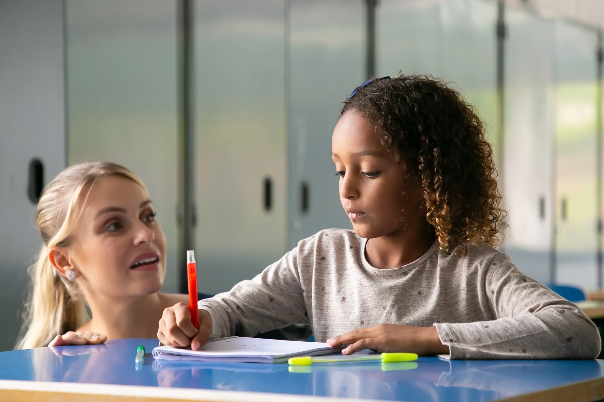 positive-female-school-teacher-helping-curly-haired-girl-her-task